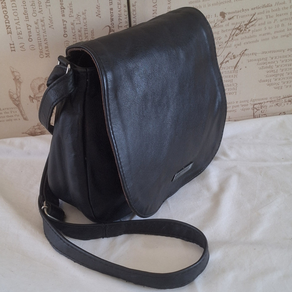 Black leather bag on a textured surface with an old book background